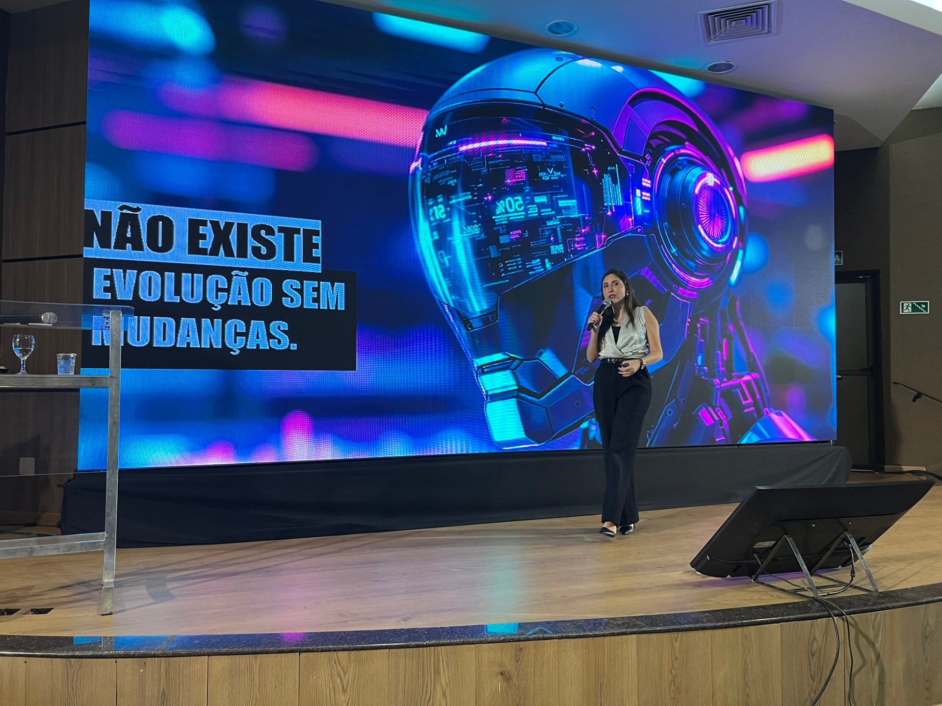 Erika Moraes em palco com tela de robô